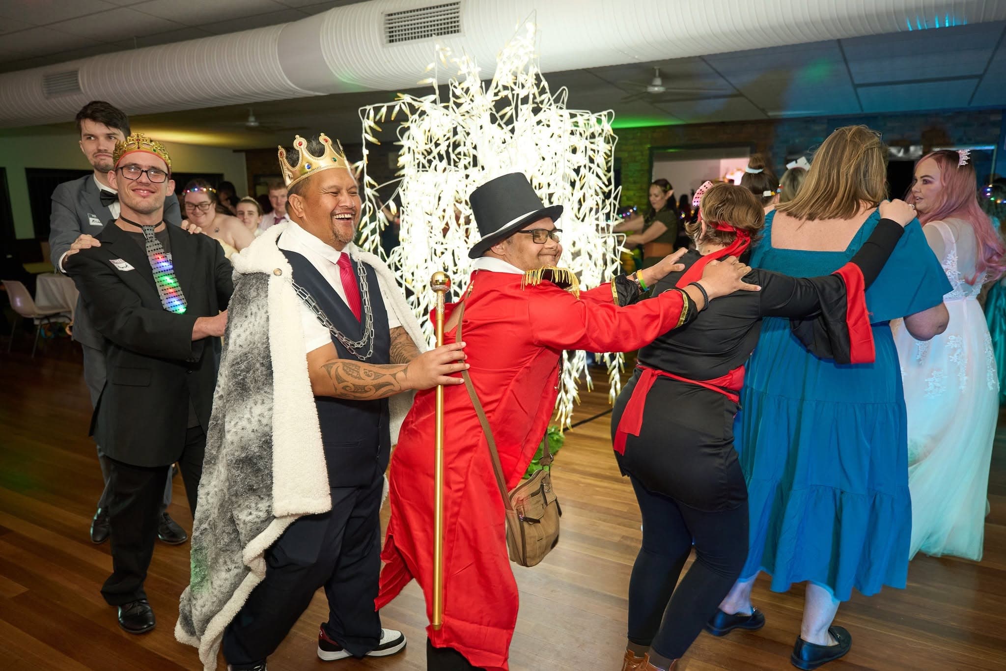 A conga line of Freedom members in crowns and costumes at the Freedom Ball